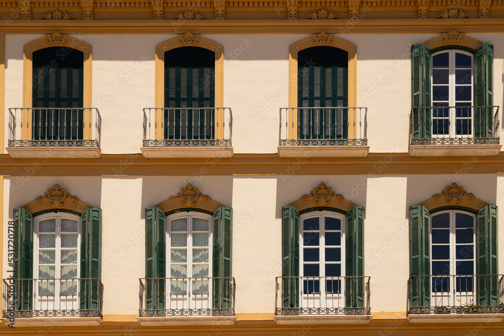 Facade with balconies and shutters of a stately home on Plaza de la Merced in the city of Málaga, Spain.
