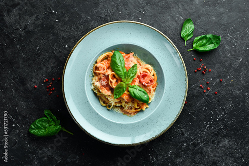 Pasta with chicken fillet, tomatoes and basil in a plate. Italian dish. On a black stone background.