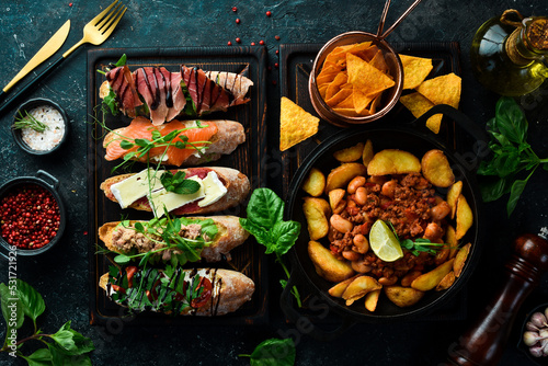 Food. Baked potatoes with meat and a set of sandwiches. On a black stone background.