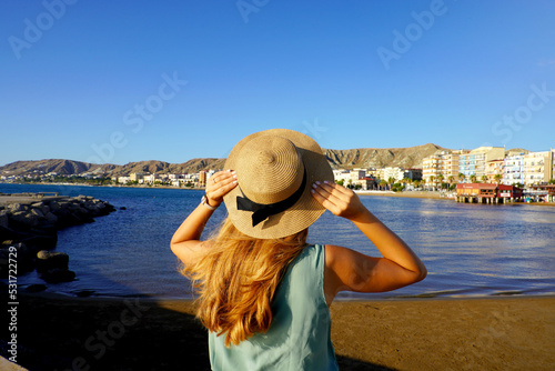 Sunset back view of girl holding straw hat in Crotone city on Calabria coast, Italy