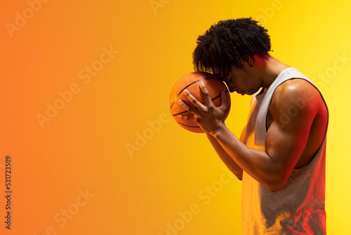 Image of biracial basketball player with basketball and copy space on orange to yellow background