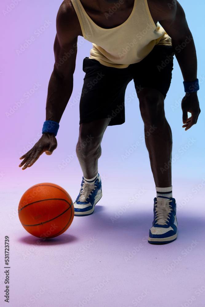 Image of african american basketball player bouncing basketball on neon purple to blue background Image of african american basketball player bouncing basketball on neon purple to blue background