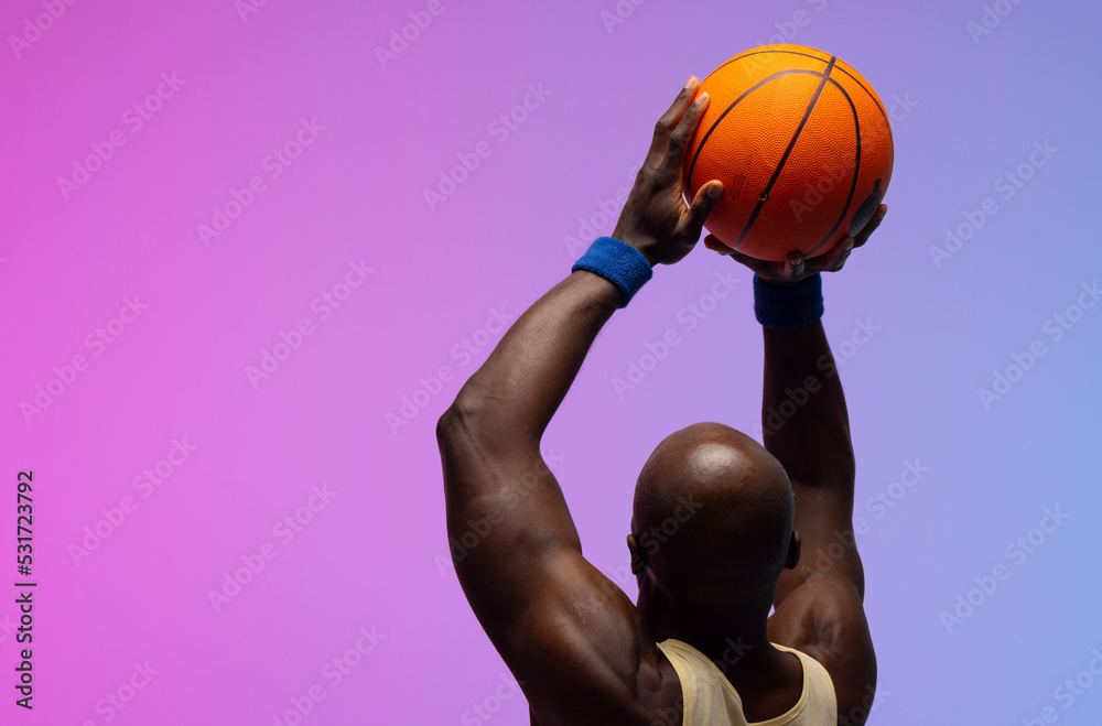 Image of african american basketball player with basketball on neon purple to pink background