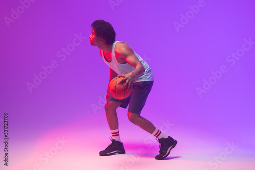 Image of biracial basketball player with basketball on neon purple background