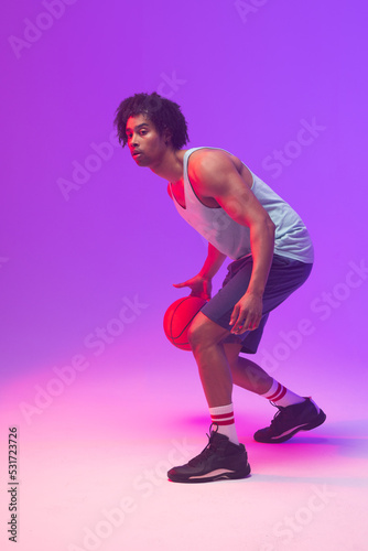 Image of biracial basketball player with basketball on neon purple background