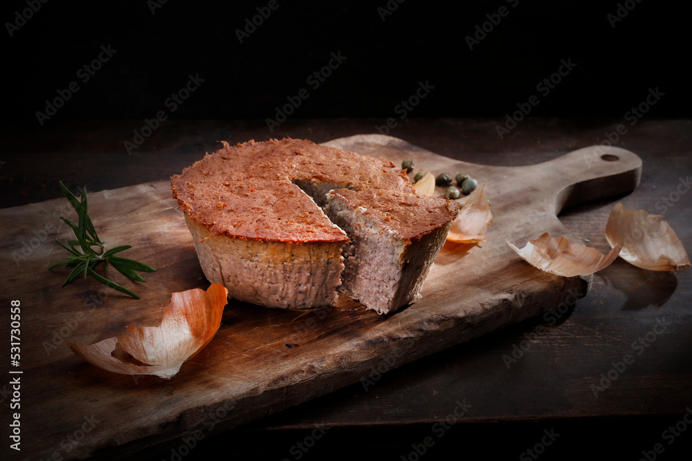 Homemade, baked meat pate. Rustic composition with cut pate on a wooden chopping board, on a black background. - obrazy, fototapety, plakaty 