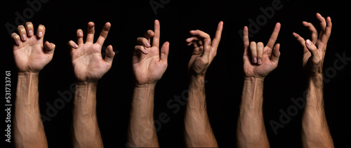 Various hand gestures on a black background. Male hand isolated on dark background