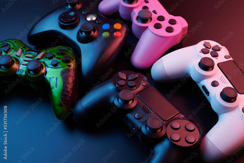 Many different video game controllers, multicolored joysticks for game console isolated on black background. Gamer controlling devices close-up