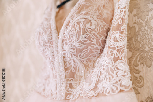 a beautiful lace wedding dress hangs on a hanger