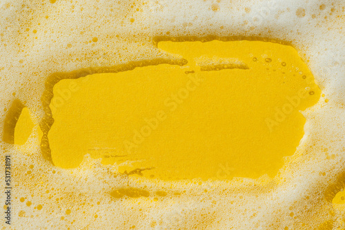 Foam on a yellow background. Soapy liquid, shower gel, shampoo swatches texture with bubbles. Natural sunshine and shadows. Skin care cleansing cosmetic in top view. Beauty concept for face and body