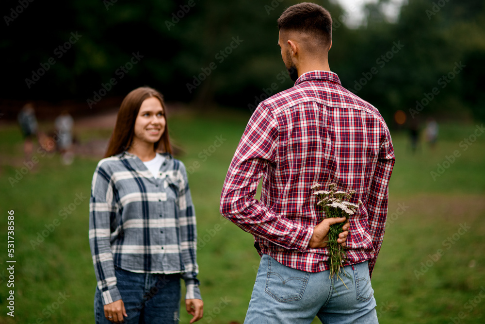 selective focus on flowers behind man back that man is going to give to woman selective focus on flowers behind man back that man is going to give to woman