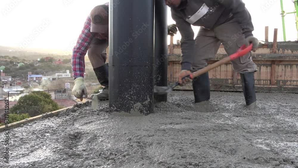 Concreting of reinforced concrete slab. Worker concretes foundation, rebar, pour cement mortar on reinforcing mesh or cage from pump concrete mixer. Builders are building a factory, hangar, house Concreting of reinforced concrete slab. Worker concretes foundation, rebar, pour cement mortar on reinforcing mesh or cage from pump concrete mixer. Builders are building a factory, hangar, house