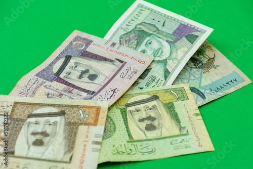 Collection of Saudi Arabia riyal banknotes on a green background. Selective focus.