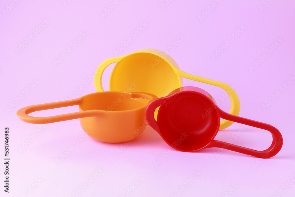 Colorful plastic measuring spoons and measuring cups on bright background Colorful plastic measuring spoons and measuring cups on bright background