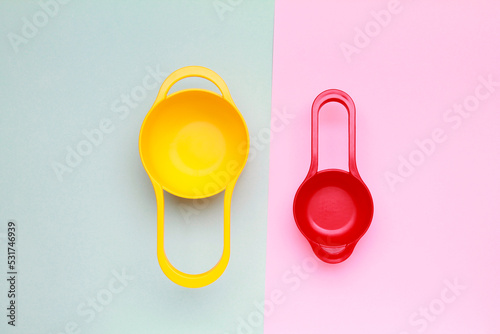 Colorful plastic measuring spoons and measuring cups on bright background top view