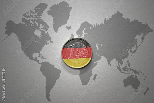 euro coin with national flag of germany on the gray world map background.3d illustration. photo