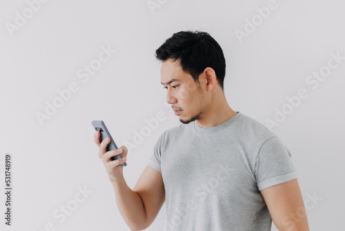 Asian man seriously concentrated on smartphone isolated on white background. © Sevendeman