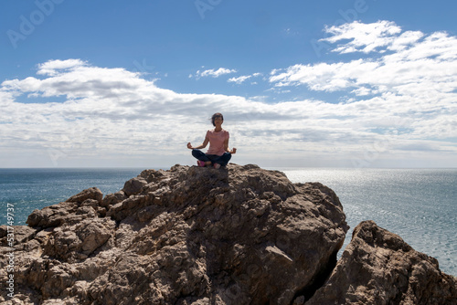 Woman doing yoga on a rock above the sea
