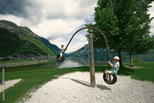 Two brothers ride on a swing from car tires at Hallstatt, Austria.