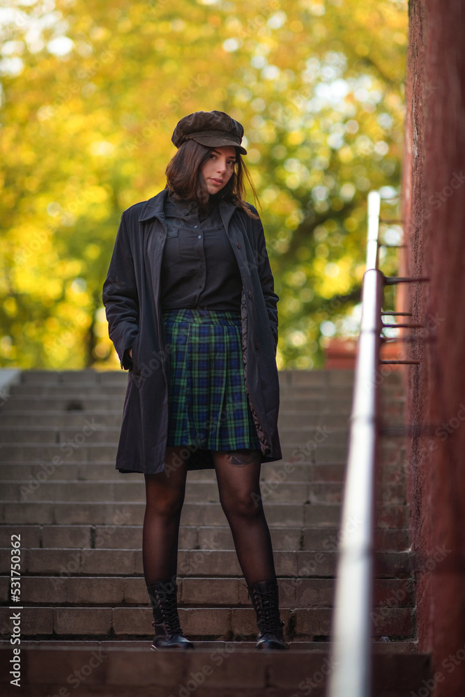 Portrait of a young beautiful girl in dark clothes on the steps in the park.