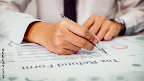 Businessman signing consent documents.Financial statistics, infographics papers, check sums, forex profits, loans.