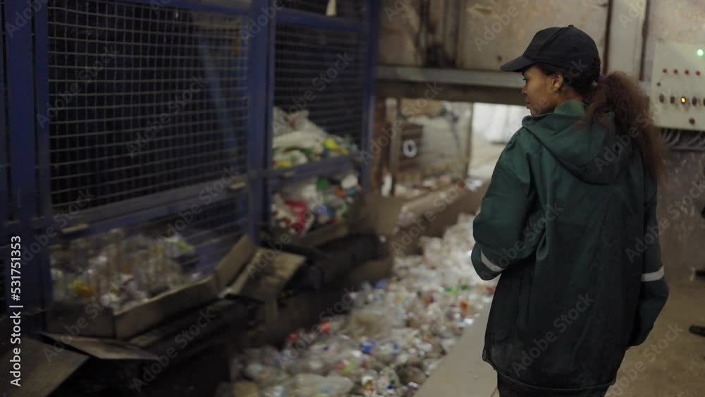 A young African-American woman checks a conveyor belt at a recycling plant. Pollution control A young African-American woman checks a conveyor belt at a recycling plant. Pollution control