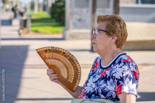 Close portrait, older woman with a hand fan outdoors photo
