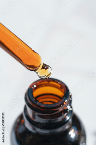 Open amber bottle with dropper pipette with serum or essential oil. Skincare products, natural cosmetic on white background. Medicine and beauty concept for face care. Selective focus in the center
