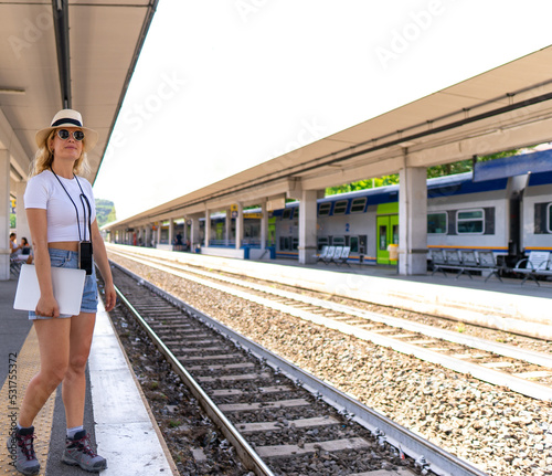 Girl waits for train at station for her next destination, wearing a backpack, hat and sunglasses, digital nomad and concept of transportation and travel © victor cuenca lopez