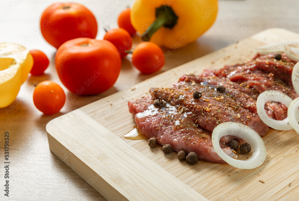 Raw beef with onions marinated with spices on light texture background.Meat cooking recipe.Juicy steak on a bamboo board, close-up. Place for text, space for copy. Raw beef with onions marinated with spices on light texture background.Meat cooking recipe.Juicy steak on a bamboo board, close-up. Place for text, space for copy.