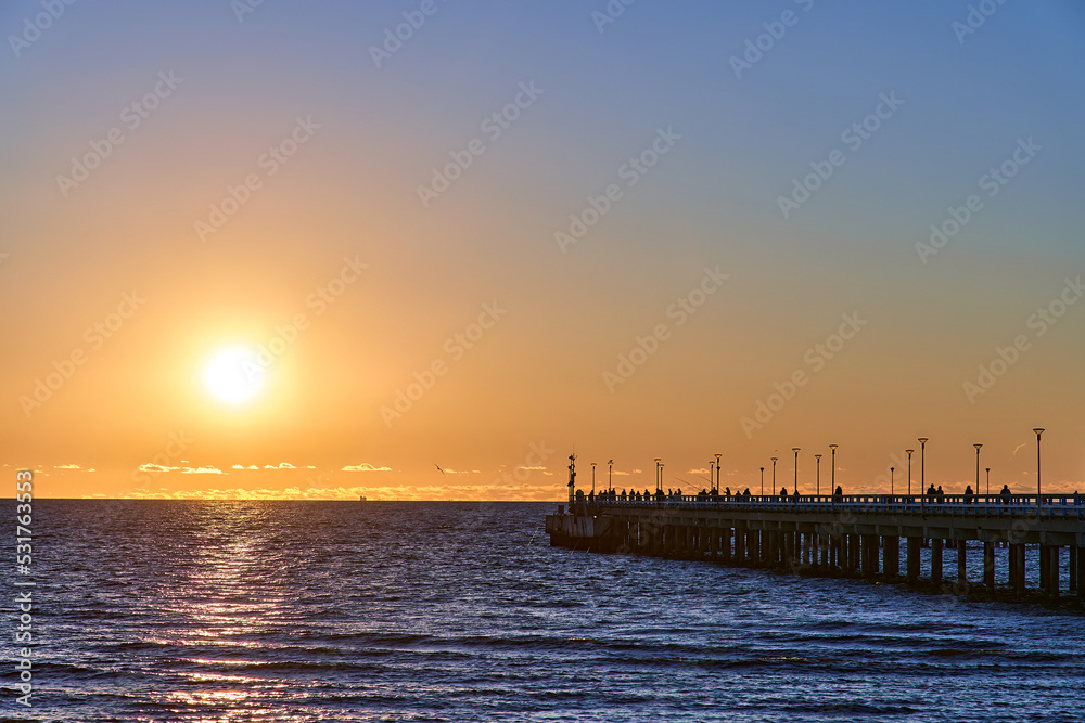 Orange sunset in the sea near a wooden pier Orange sunset in the sea near a wooden pier