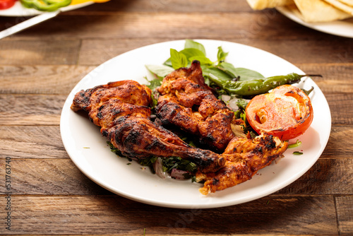 Grilled chicken with tomato and salad served in a dish isolated on wooden table background side view of fastfood