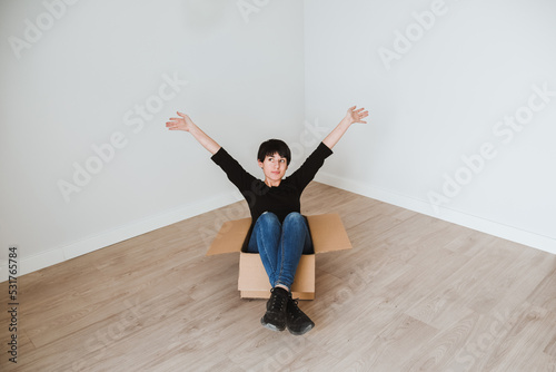 Una mujer joven con el pelo corto dentro de una caja de cartón en una habitación vacía. Concepto de mudanza y amueblar un nuevo hogar. Vida en solitario. Independizarse. photo