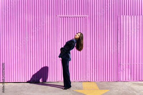 Woman wearing blue suit posing near pink shutter.