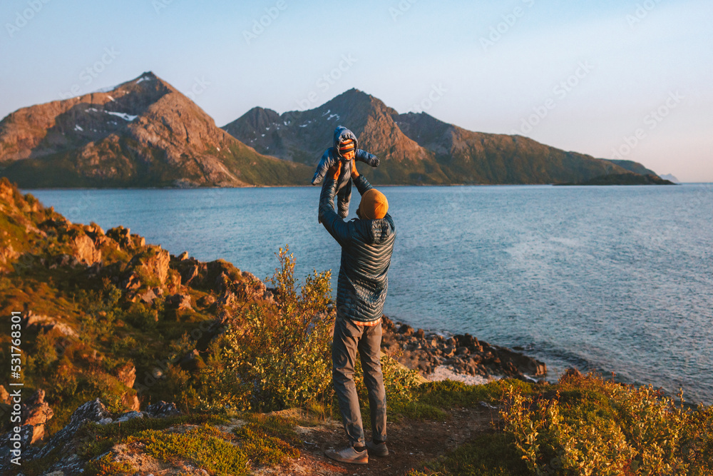 Father holding up baby family having fun outdoor travel together in Norway active vacations healthy lifestyle man with infant child walking at fjord - obrazy, fototapety, plakaty 