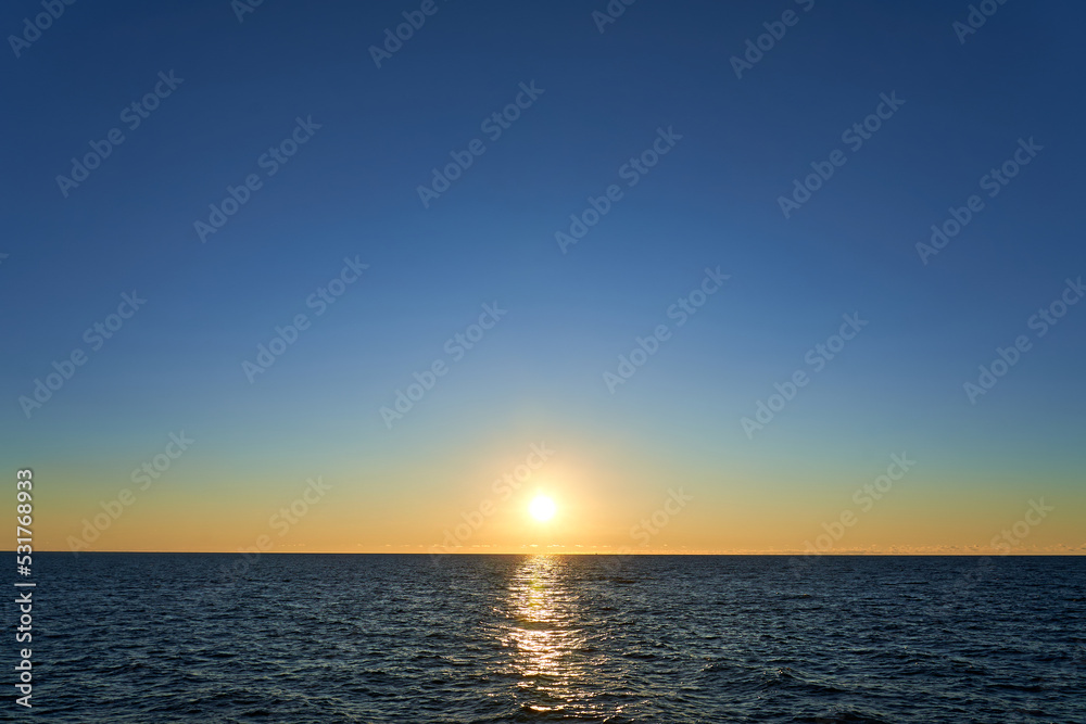 Sunset in the sea. The sun slowly goes behind the sea line