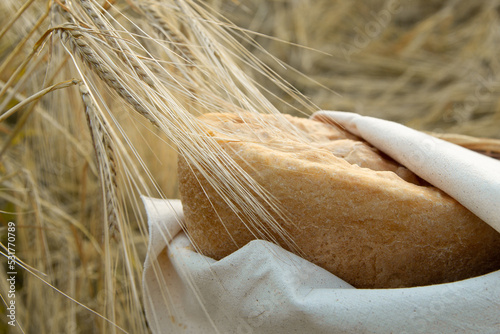 natural bread in ears of wheat, hot bread, wrapped in a linen napkin, natural colors, organic bread