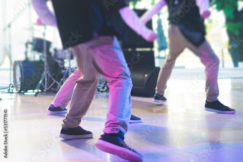 Group of hip-hop dancers performance on a stage, modern contemporary street dance with break dancing in studio, hip hop dance training in a ballroom, legs in sneakers close up