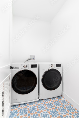 A laundry room with a white washer and dryer on a mosaic tile flooring.