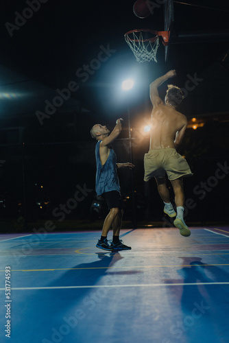 Man friends play basketball in the open area. Night basketball game in the yard.