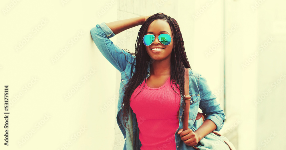 Portrait of happy smiling young african woman model wearing backpack, sunglasses, colorful clothes on white background Portrait of happy smiling young african woman model wearing backpack, sunglasses, colorful clothes on white background