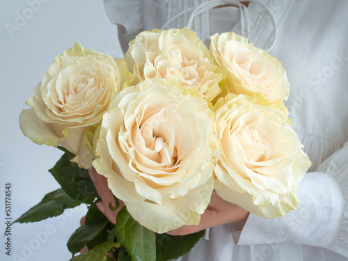 Young woman in a white dress holding bouquet of flowers on white background with copy space.
