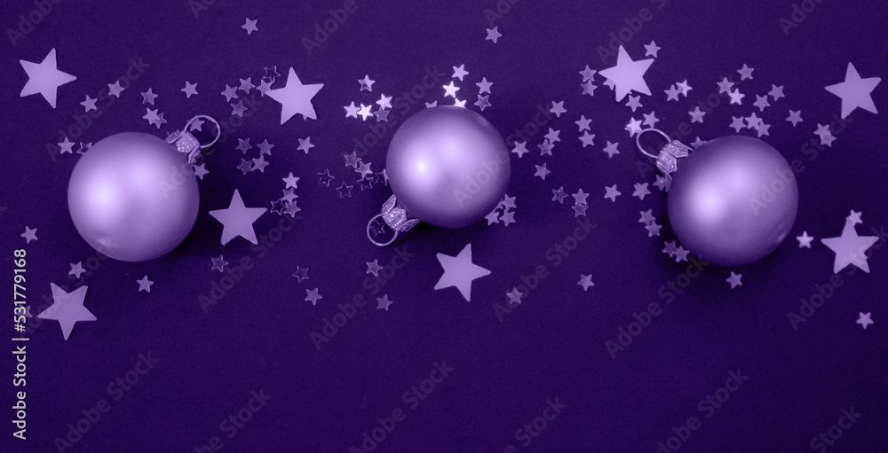 Christmas balls with stars confetti toned in light purple background, color of the year 2022 very peri.