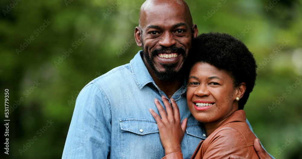 African couple embracing together outside portraits looking at camera standing outside