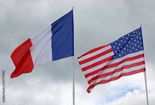 American and French flags with blue sky background waving together photo