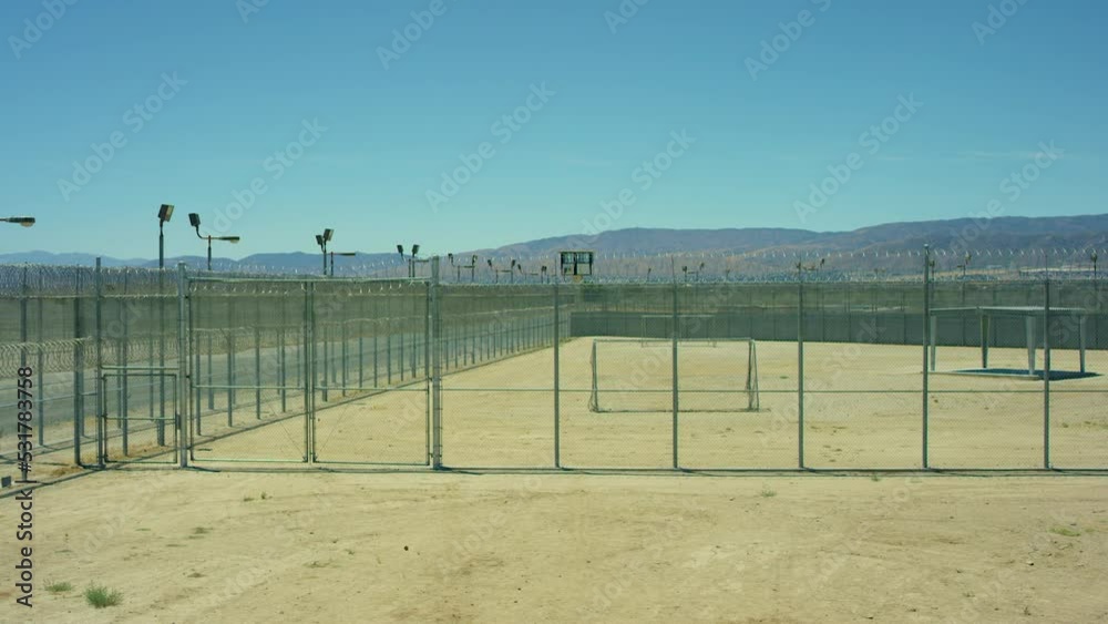 Electric chain-link fence with barbed wire of the prison, High barbed wire fence around prison or secret military base, detention facility, watchtower, last sun rays penetrating Electric chain-link fence with barbed wire of the prison, High barbed wire fence around prison or secret military base, detention facility, watchtower, last sun rays penetrating