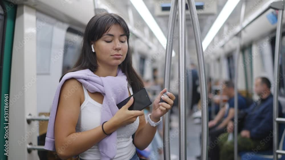A young beautiful woman stands in a subway car, puts on wireless headphones, turns on music on her phone, starts dancing actively. Slow motion 120fps footage A young beautiful woman stands in a subway car, puts on wireless headphones, turns on music on her phone, starts dancing actively. Slow motion 120fps footage