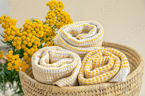 Towels made of natural materials in a wicker basket on a uniform background. Handmade