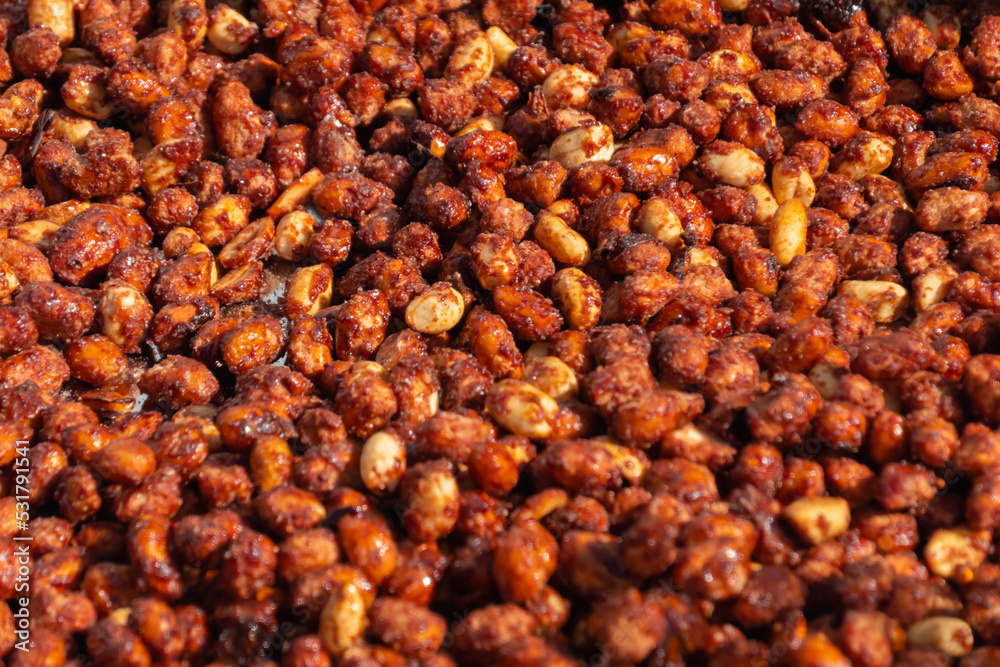 Fototapeta premium Heap of roasted caramelized sugared peanuts with warm and contrast sunlight illumination at summer outdoor food market - close up. Cookery, dessert, gastronomy and street food concept