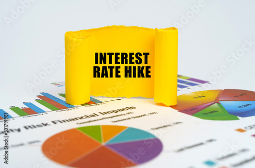 Against the background of graphs and charts, a yellow paper plate with the inscription - Interest rate hike